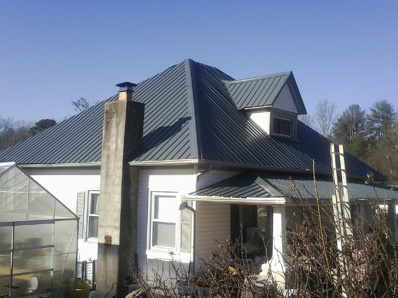 Dark blue standing seam metal roof on a white farmhouse with dormer — Slate & Tile Roof Repair by Roofing Brothers in Moreno Valley