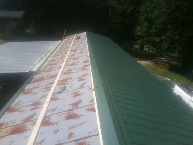 Old rusted panels beside newly installed green metal roofing — Wind Damage Roof Repair by Roofing Brothers in Moreno Valley