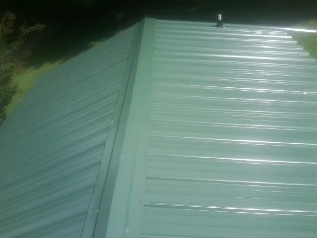 New green metal panels meeting at the ridge of a roof — Flat Roof Repair work by our crew in Moreno Valley