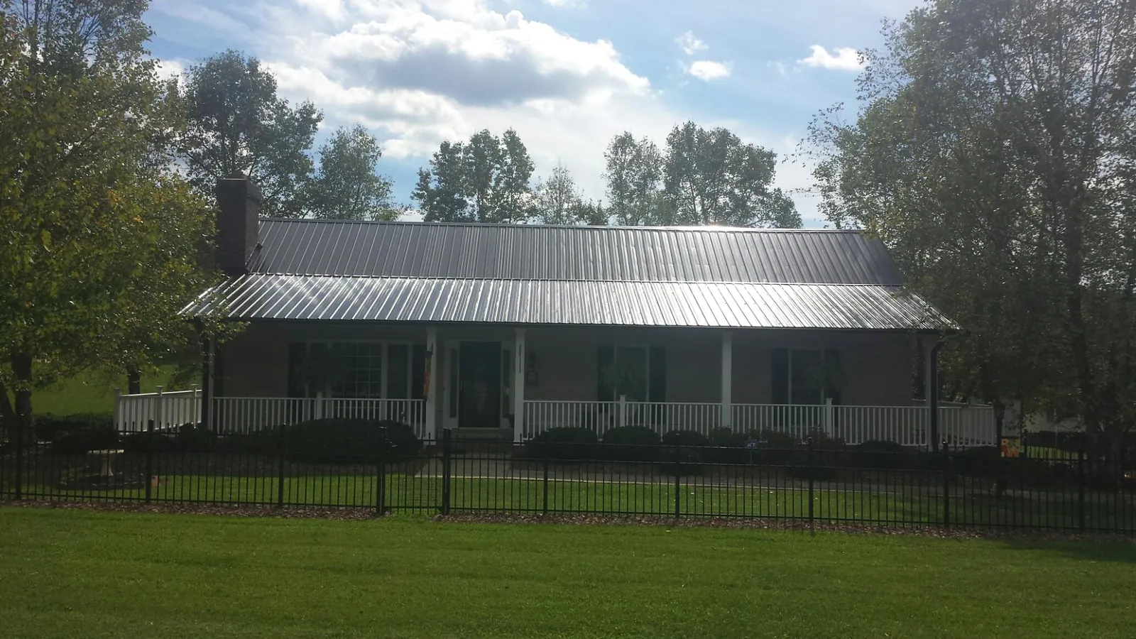 Gray metal roof on a brick ranch with a full width front porch — Gutter Guard Installation work by our crew in Moreno Valley