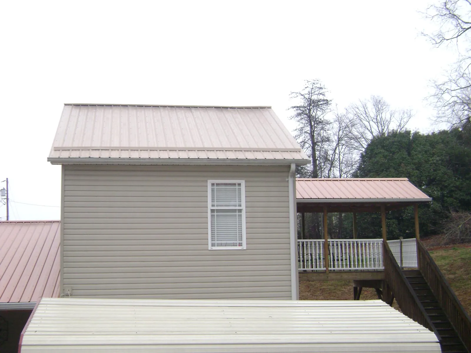 Tan metal roofs on a two story addition and attached porch, from a Roof Replacement job in Moreno Valley